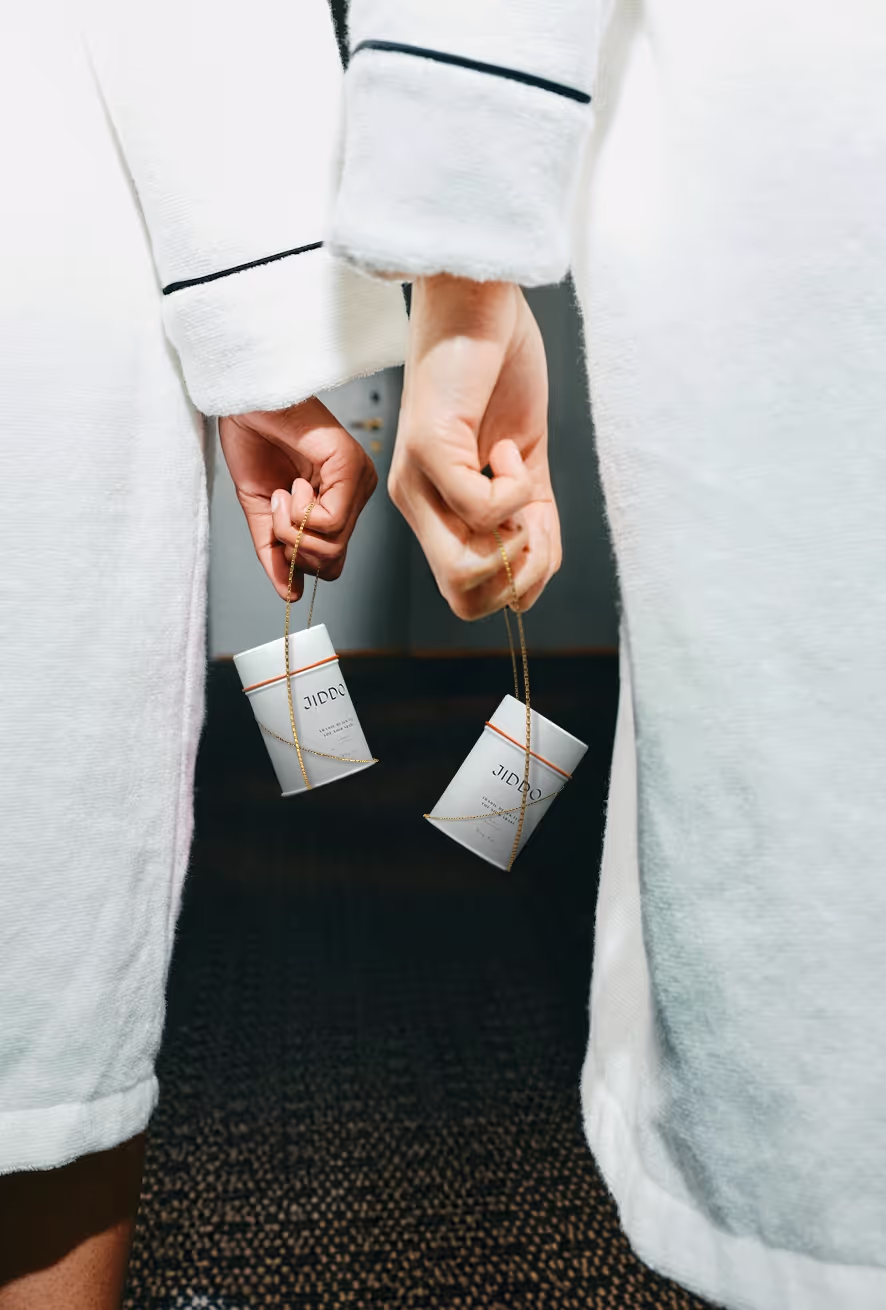 Two JIDDO tea sachets held in a hotel robe
