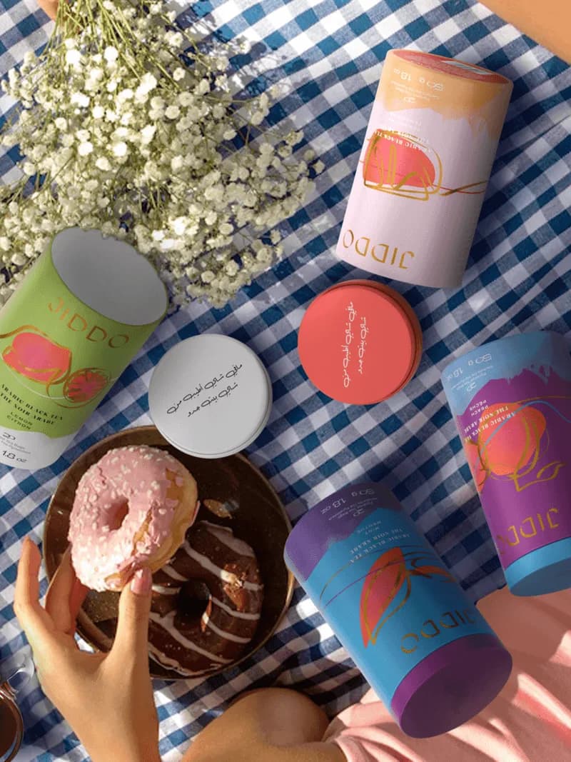 JIDDO tins and a doughnut on a gingham picnic blanket